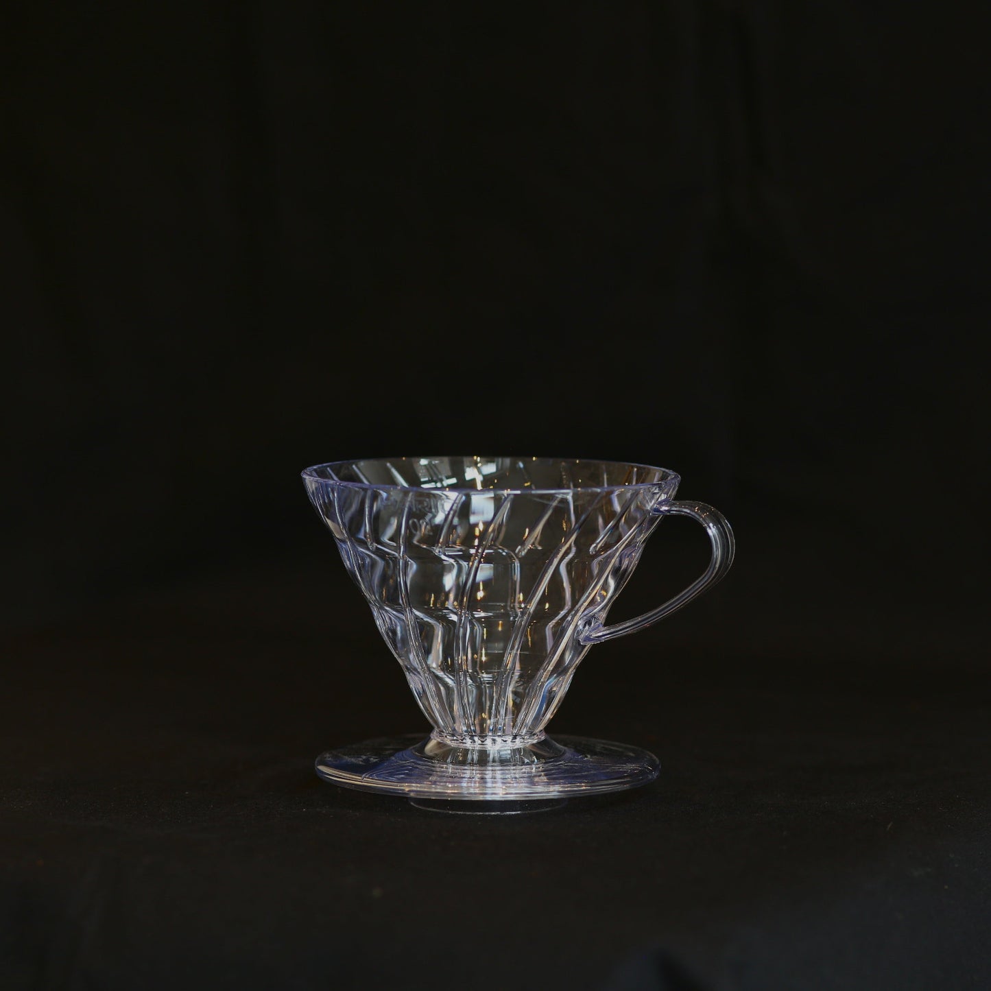 Ein transparenter HARIO V60 Filterhaalter auf schwarzem Grund